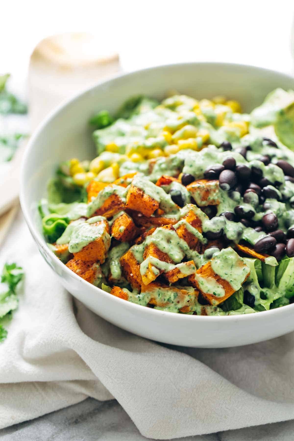 This healthy Spicy Southwestern Salad recipe has roasted sweet potatoes, black beans, corn, lettuce, and creamy avocado dressing! | pinchofyum.com