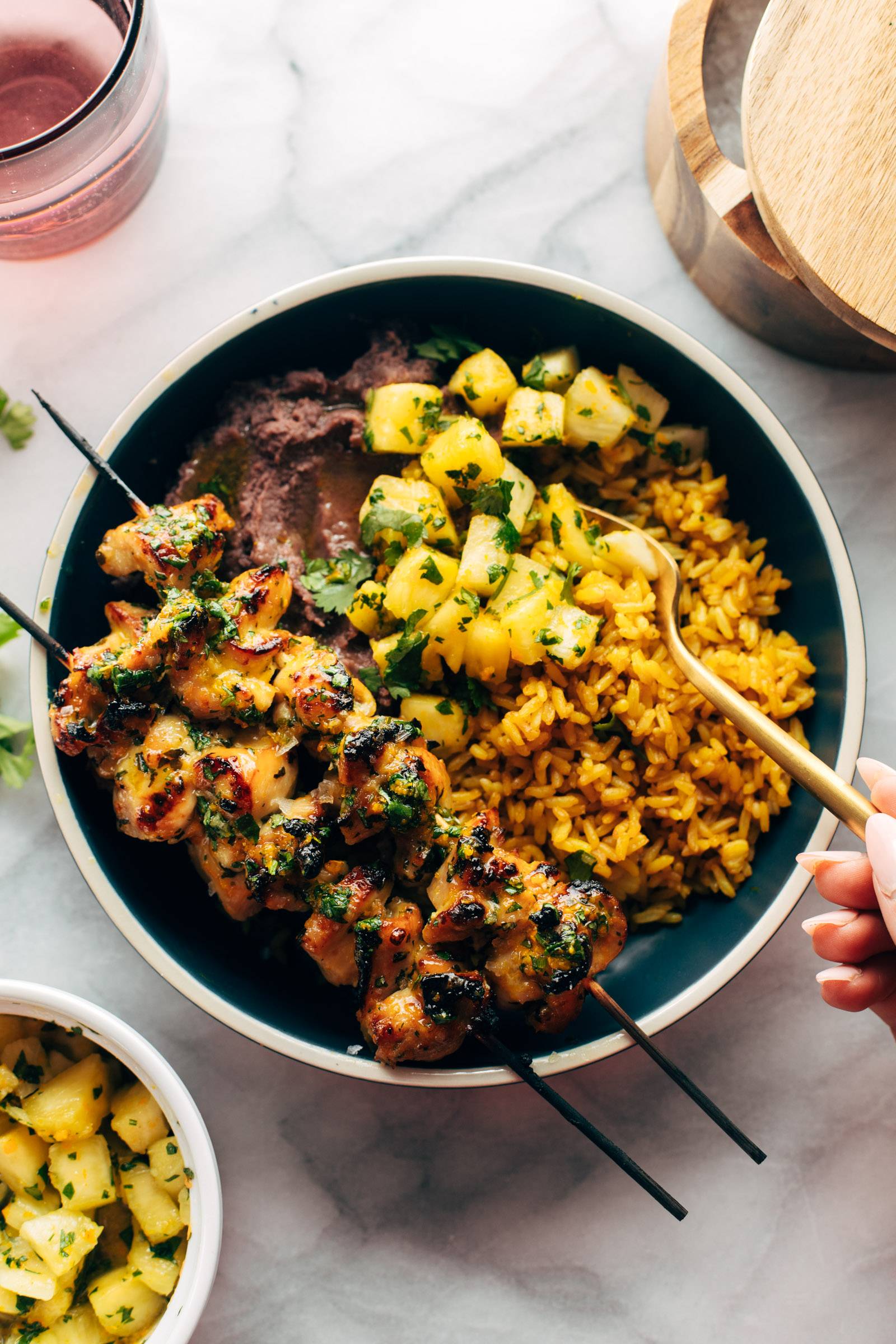 Chicken and rice in a bowl with pineapple salsa and refried beans.