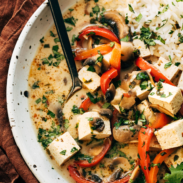 Thai coconut soup in a bowl with fresh cilantro, rice, tofu, and a spoon.