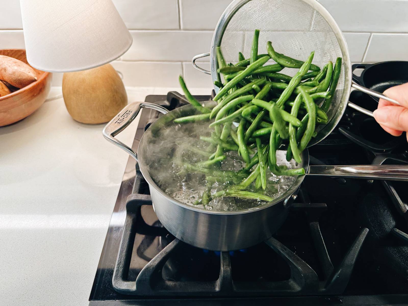 Adding green beans to a pot of boiling water.