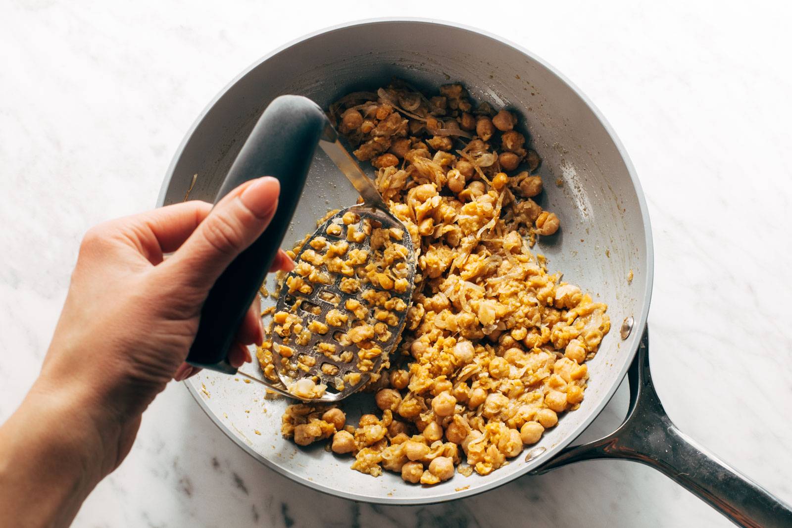 Smashing chickpeas in a pan.