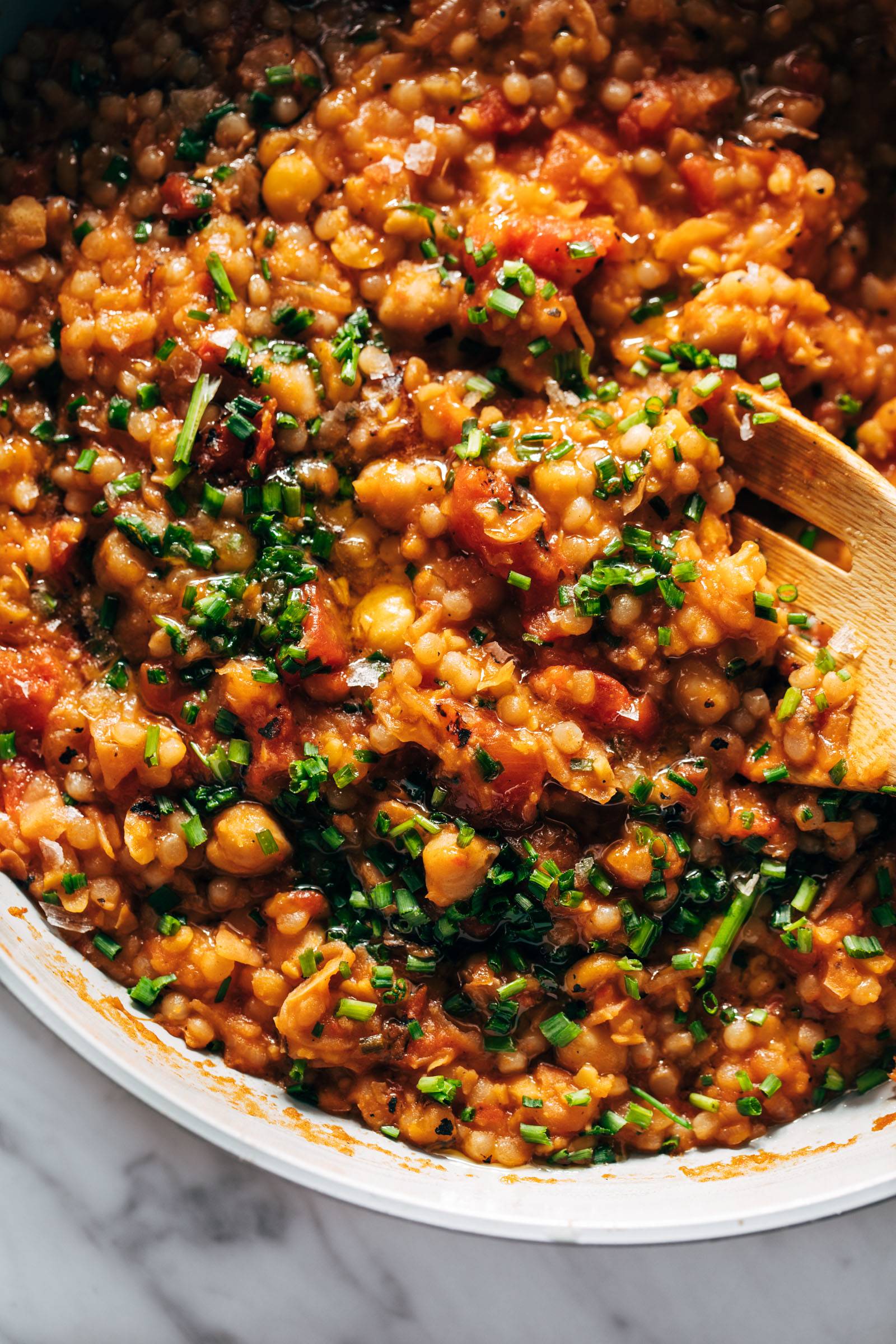 Couscous skillet in a pan with a wooden spoon.