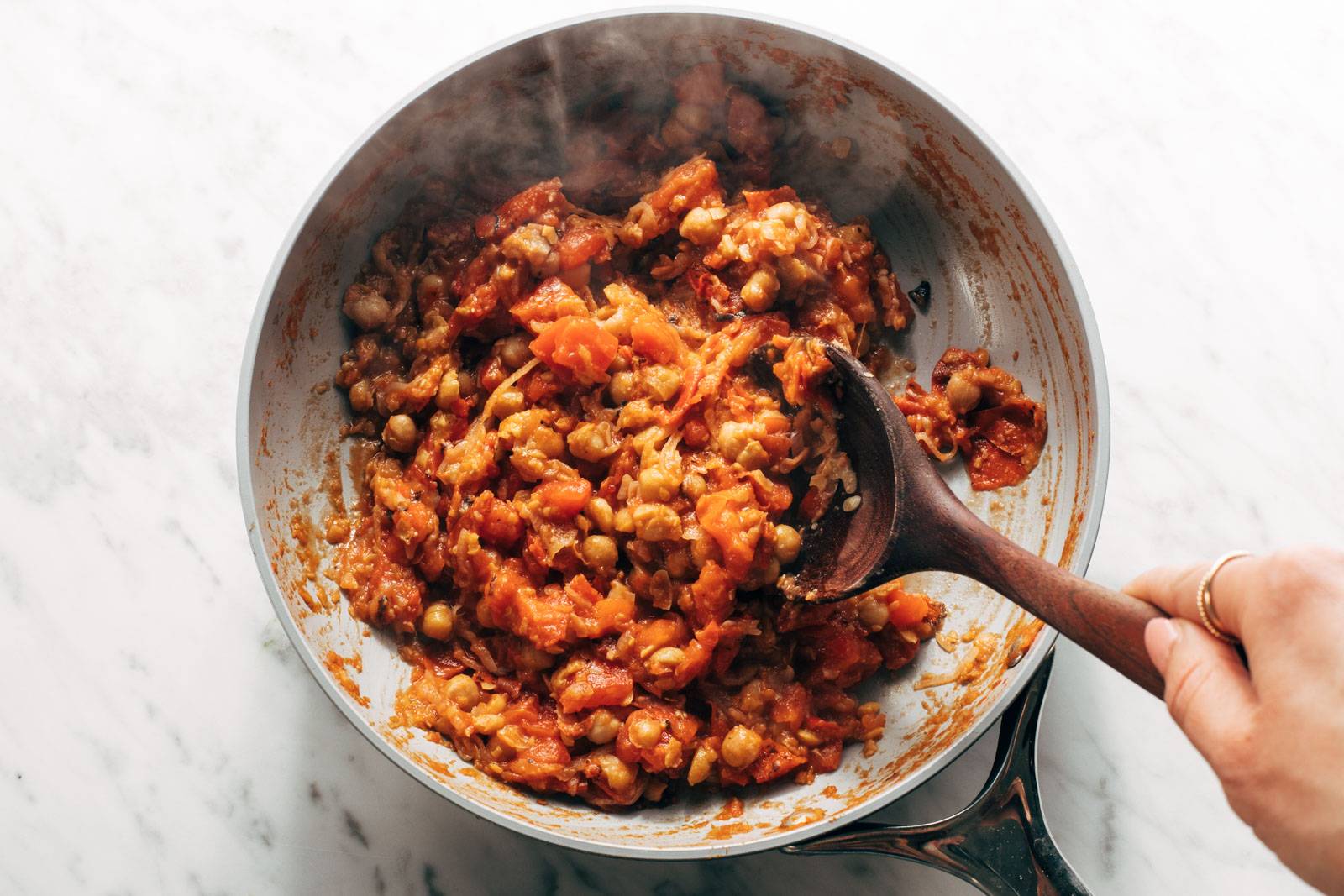 Stirring tomatoes into smashed chickpeas.