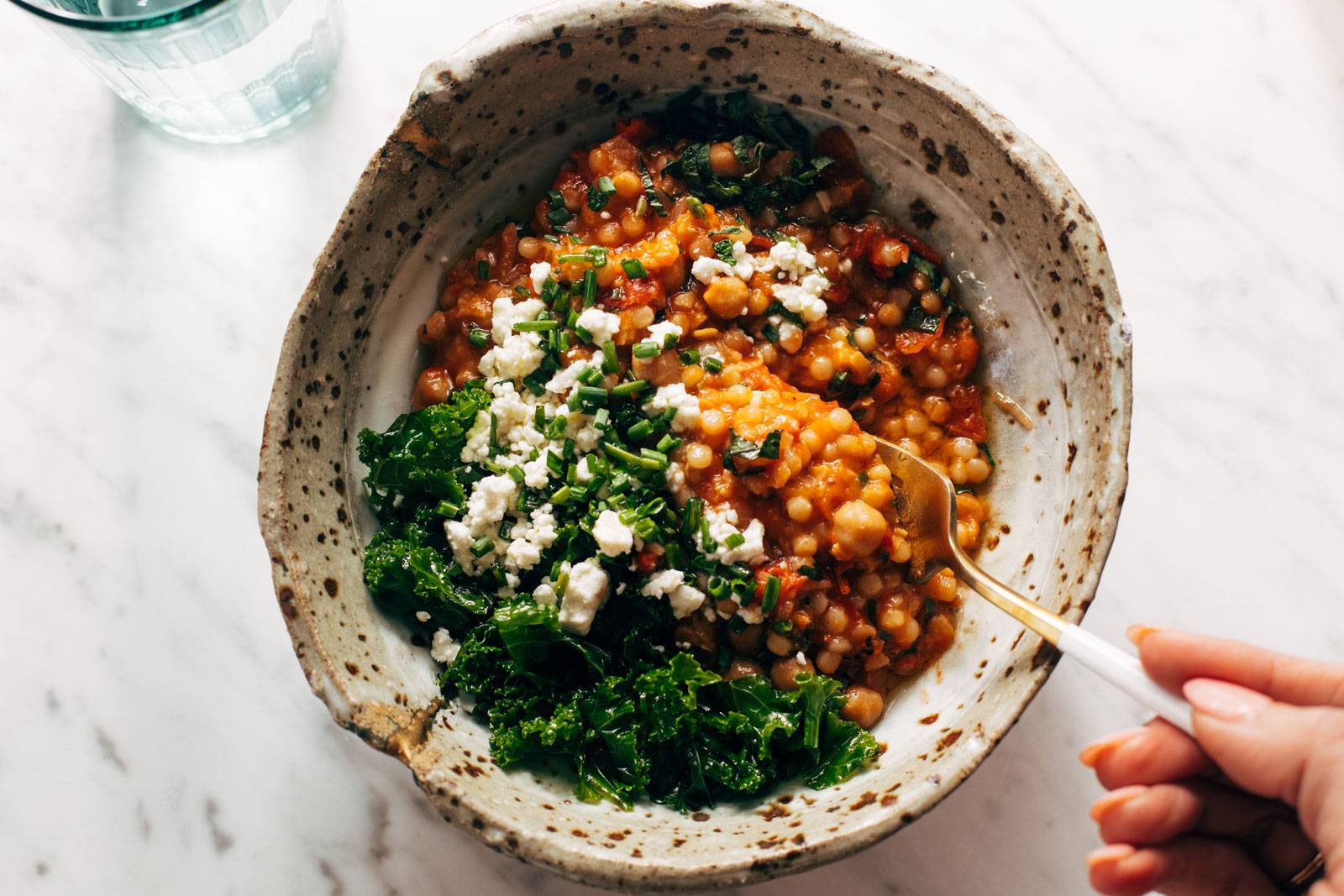 Scooping up couscous with a fork in a bowl.