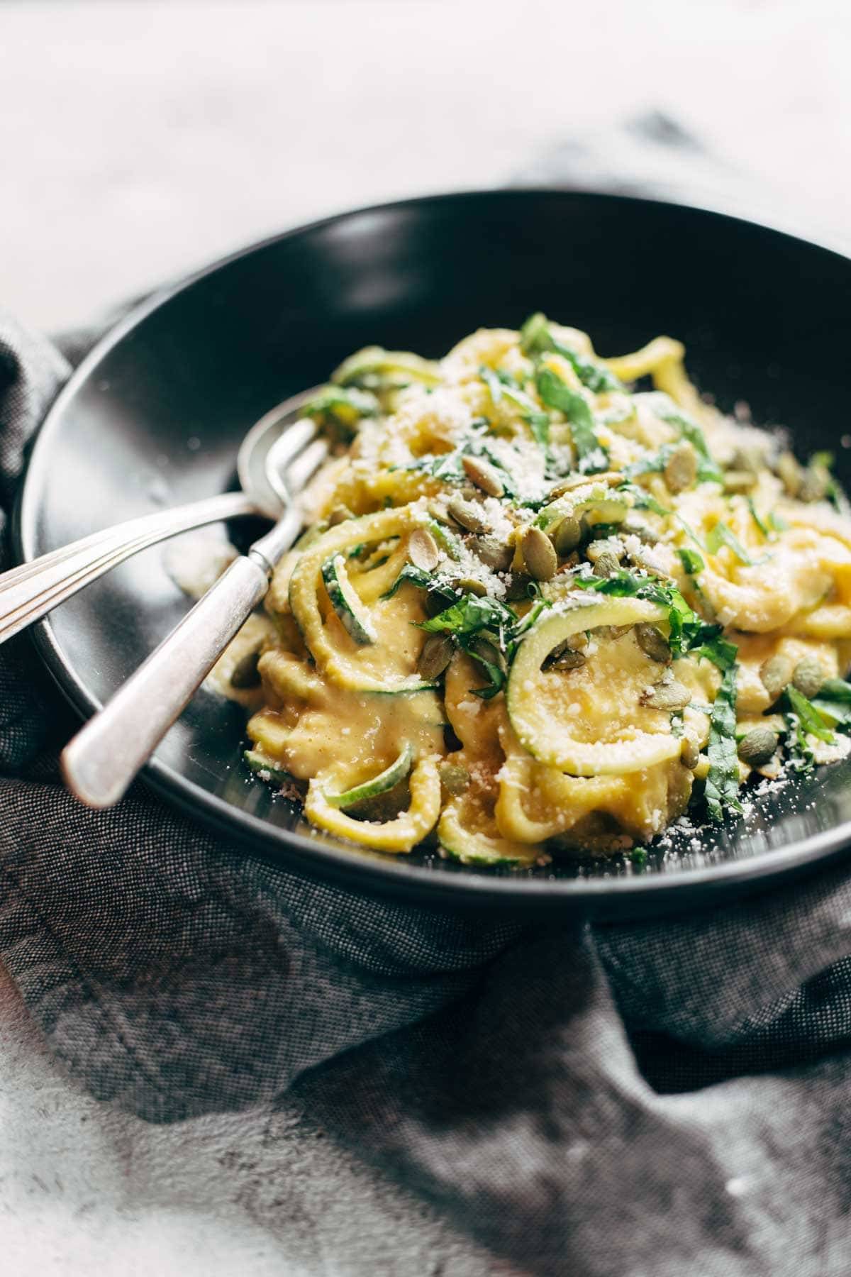 Zoodles with Creamy Corn Sauce in a bowl with a spoon and a fork.