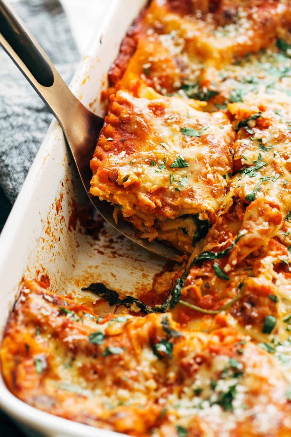 Lifting a piece of lasagna out of the pan.