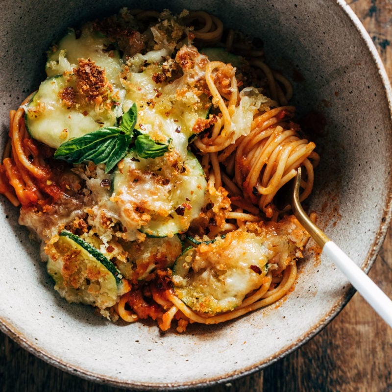 Spaghetti with roasted zucchini in a bowl with a fork.