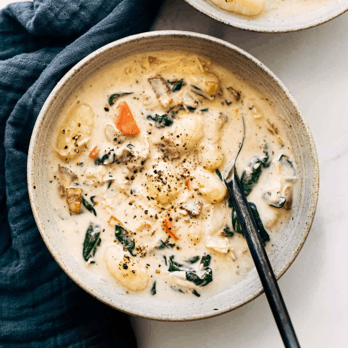 Creamy chicken gnocchi soup in a bowl with a spoon.