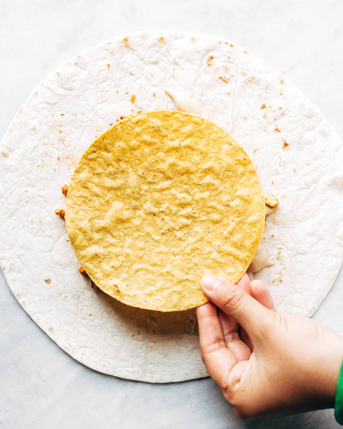 Adding tostada to vegan crunchwrap supreme.