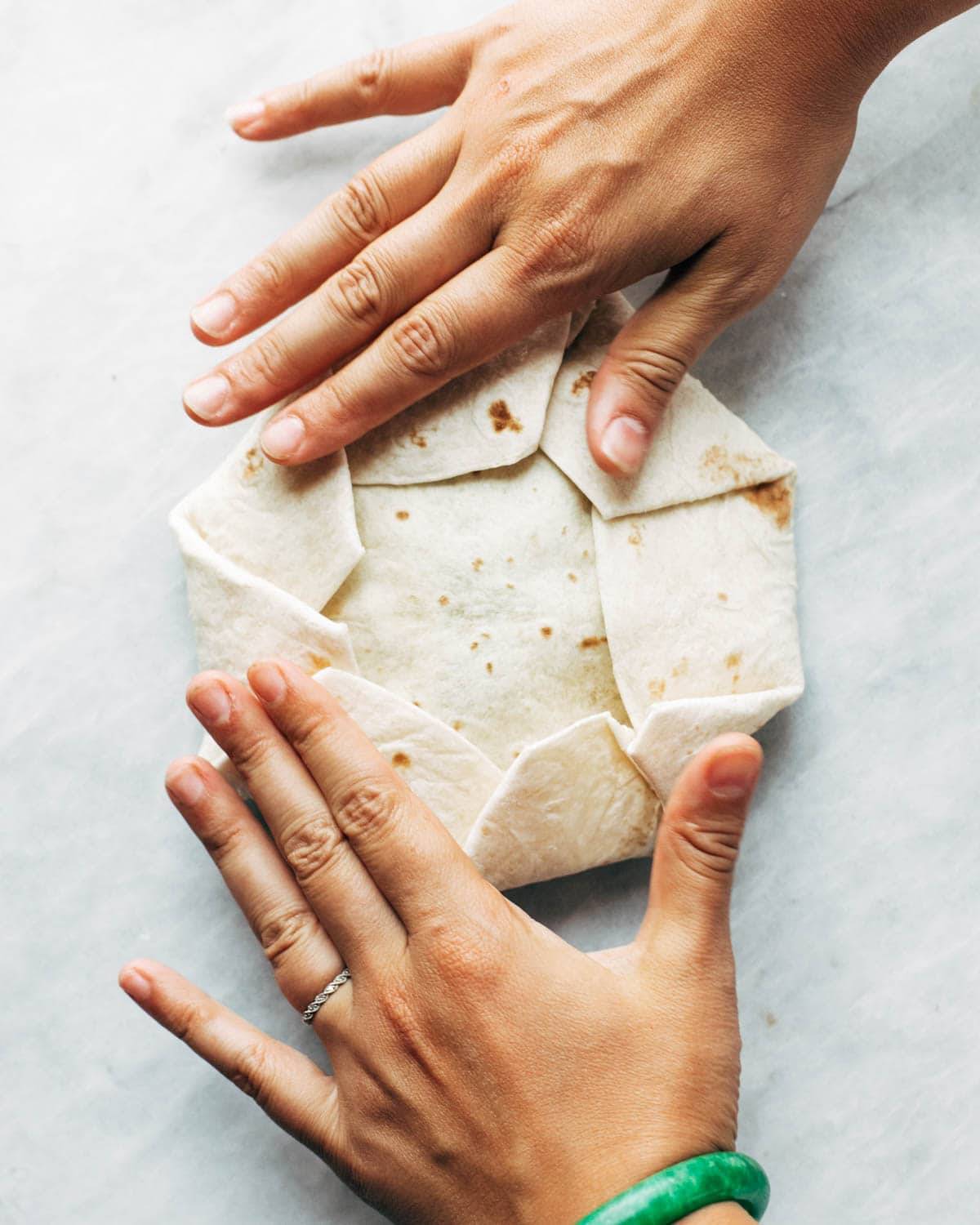 Folding up tortilla for vegan crunchwrap supreme.