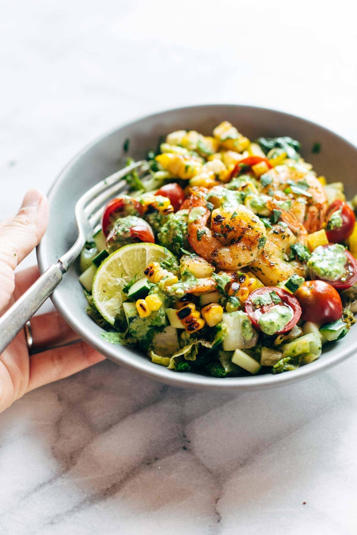 Salad in a bowl with shrimp and lime.