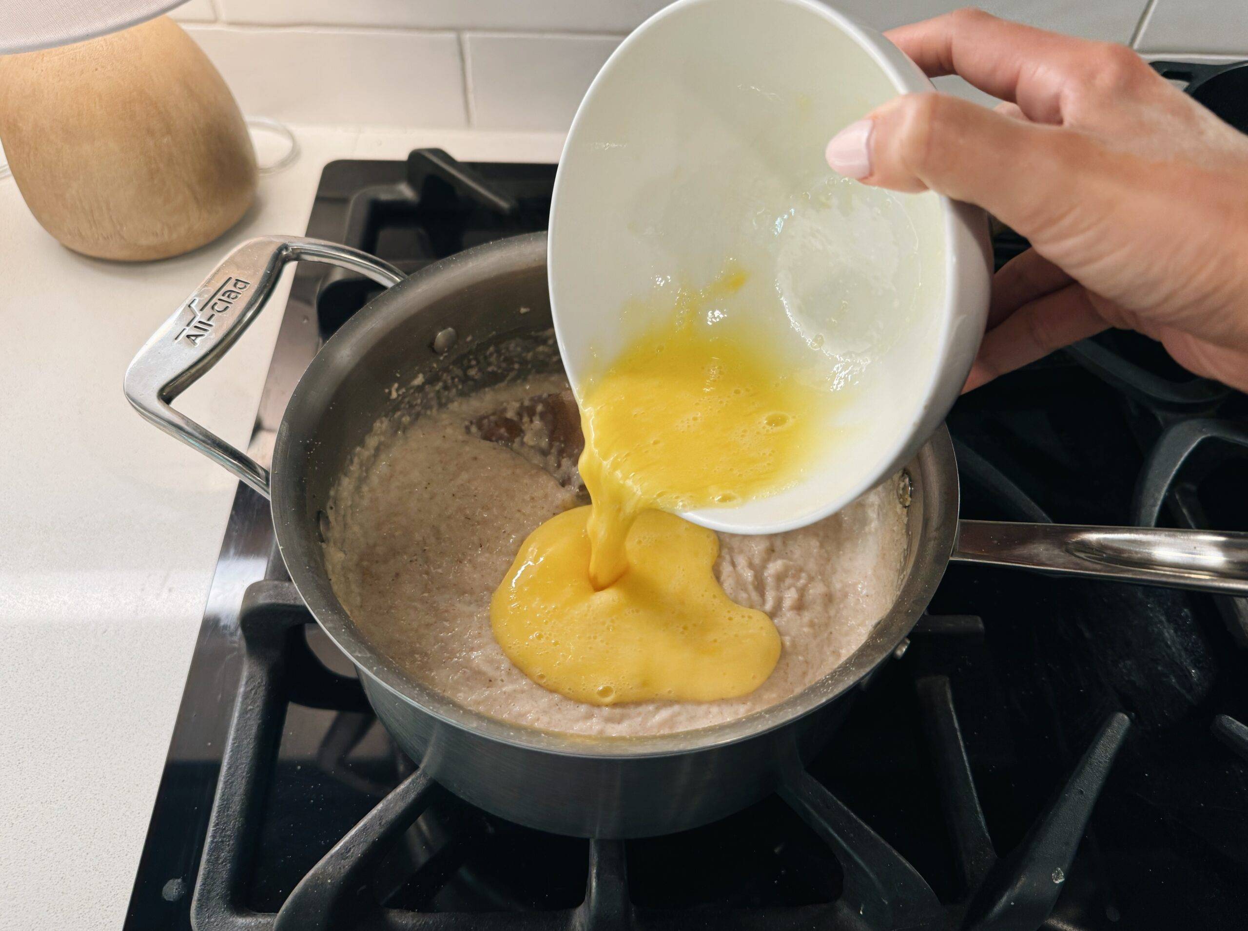 Pouring a whisked egg into the oat bran on the stove.