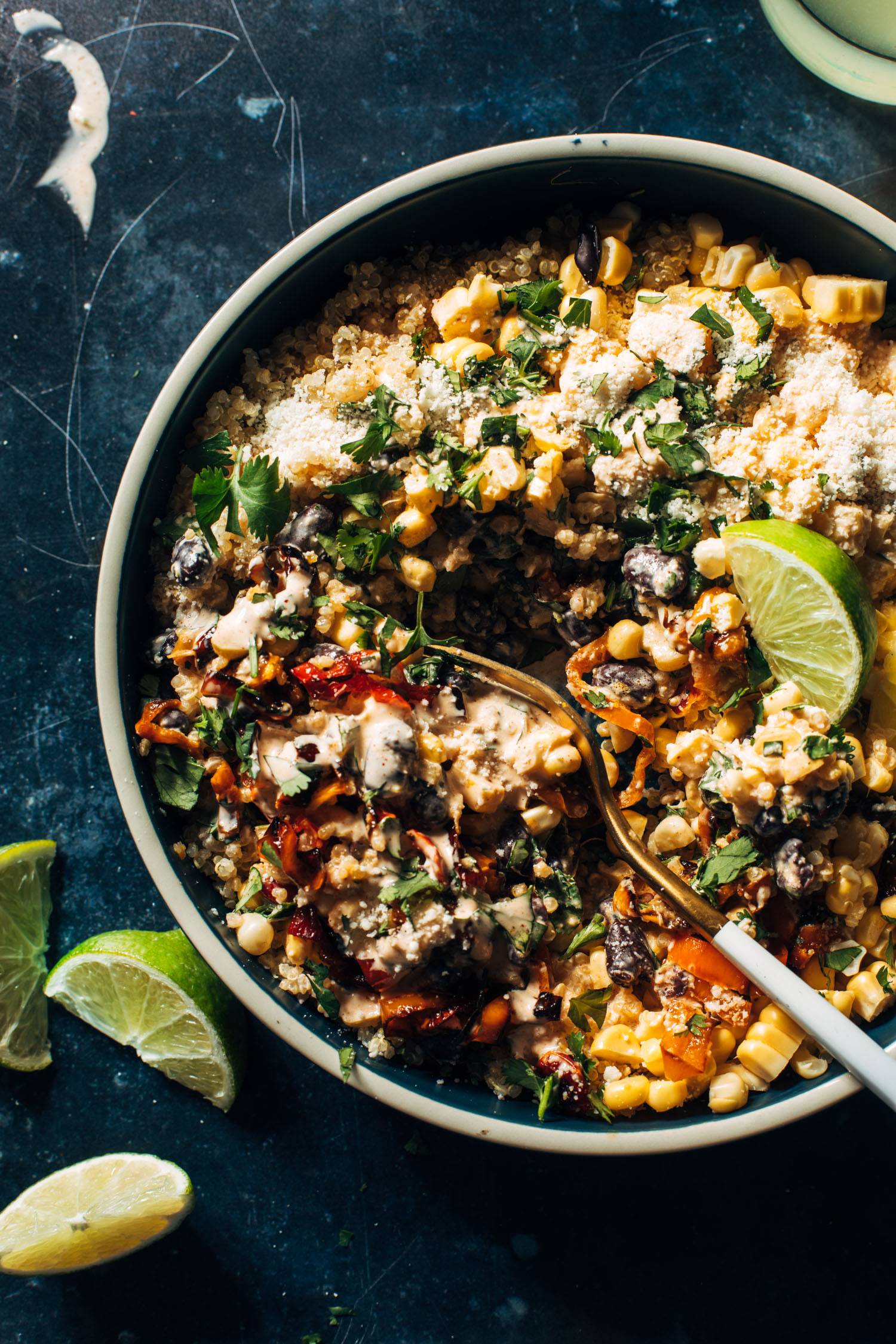 Elote quinoa salad in a bowl with cotija cheese and a fork