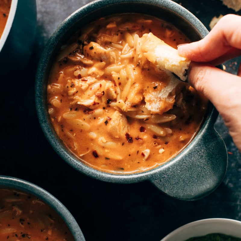 White hand dipping bread into soup