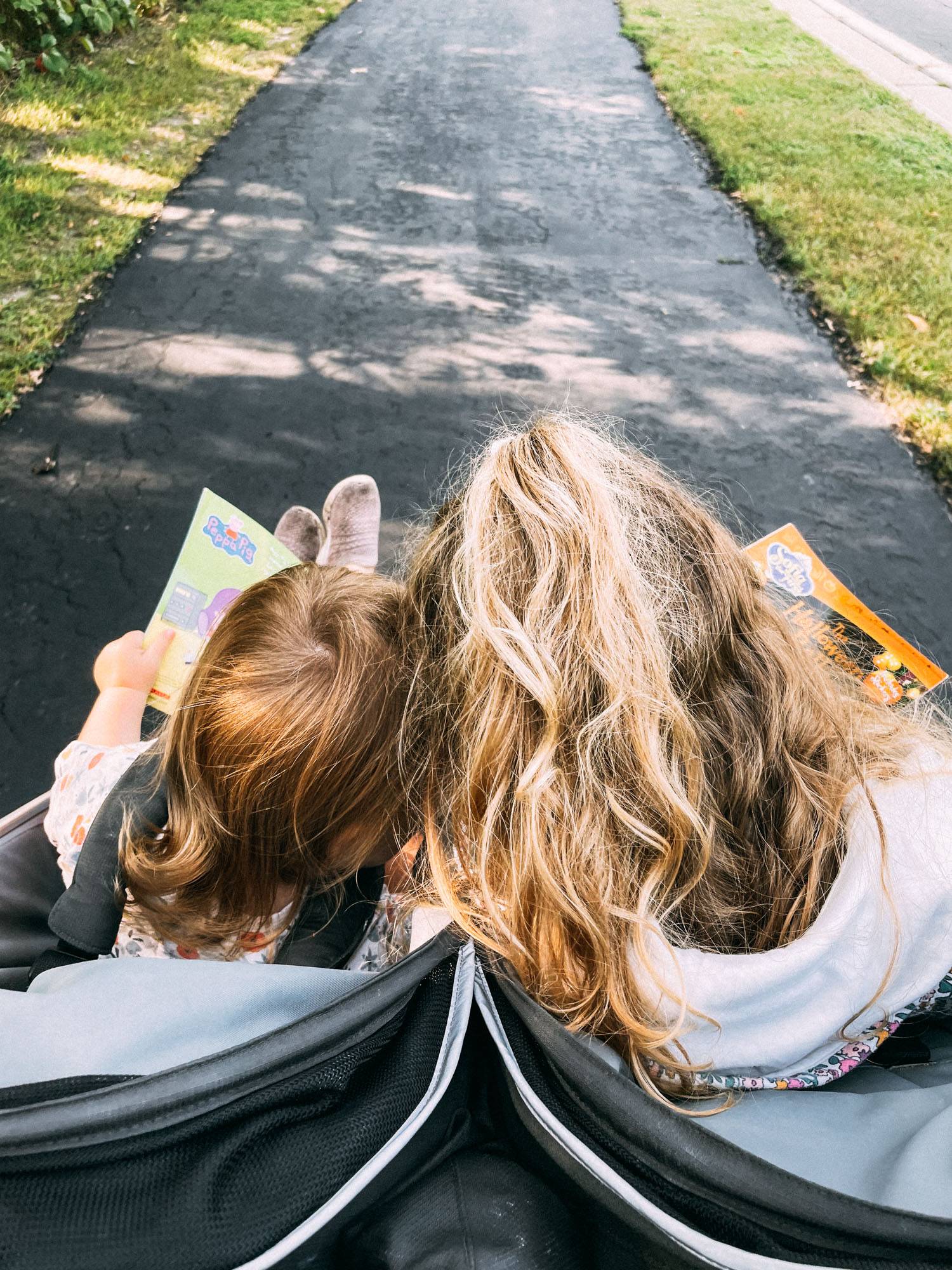 Two girls riding in a double stroller