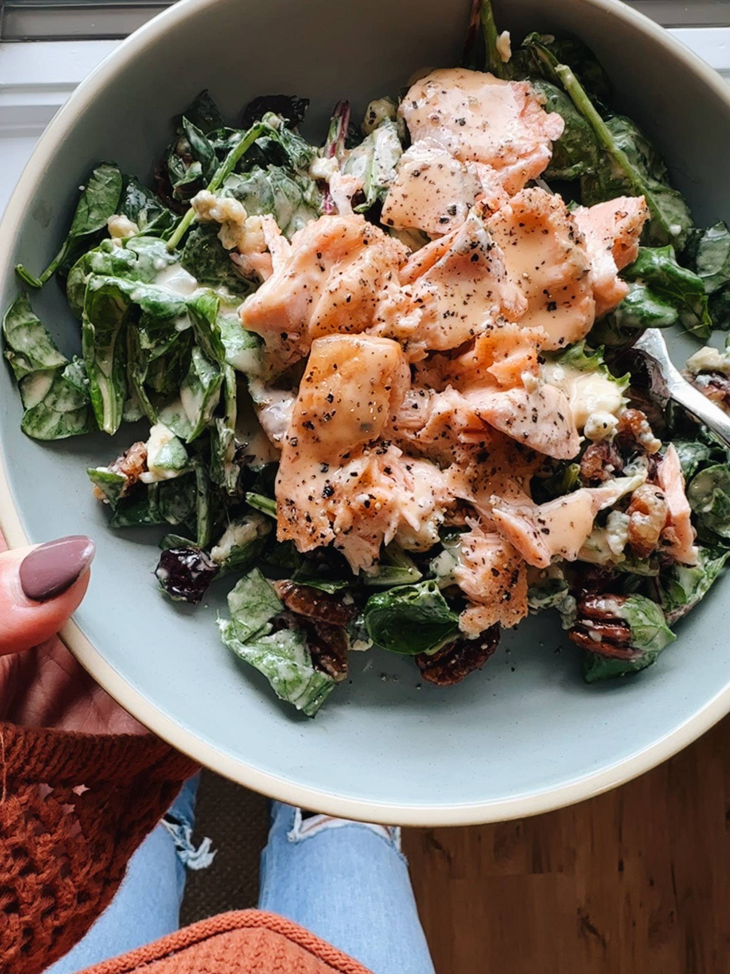 White hand holding bowl of salmon salad