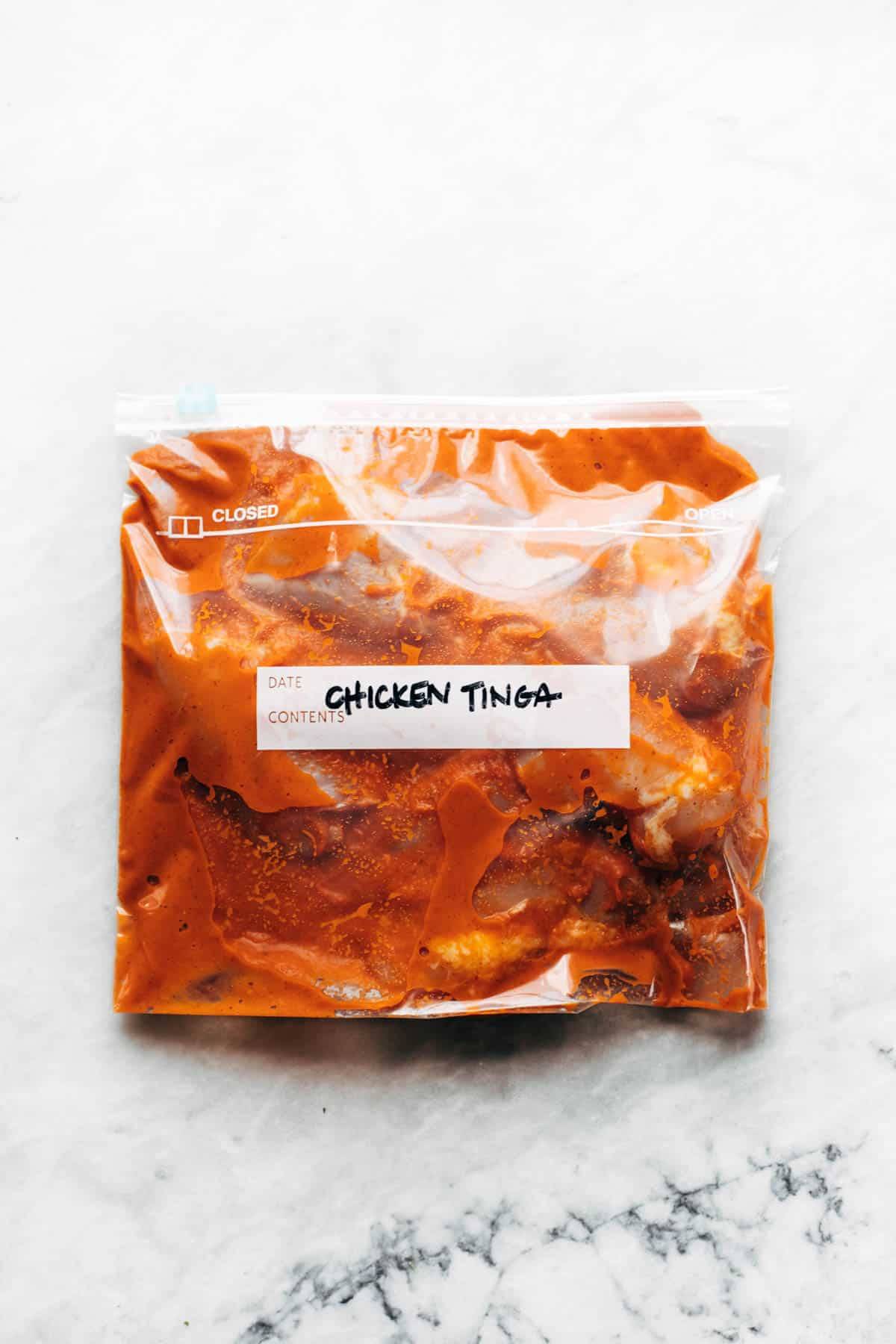 A transparent packet full of chicken tinga and with a label written over it.