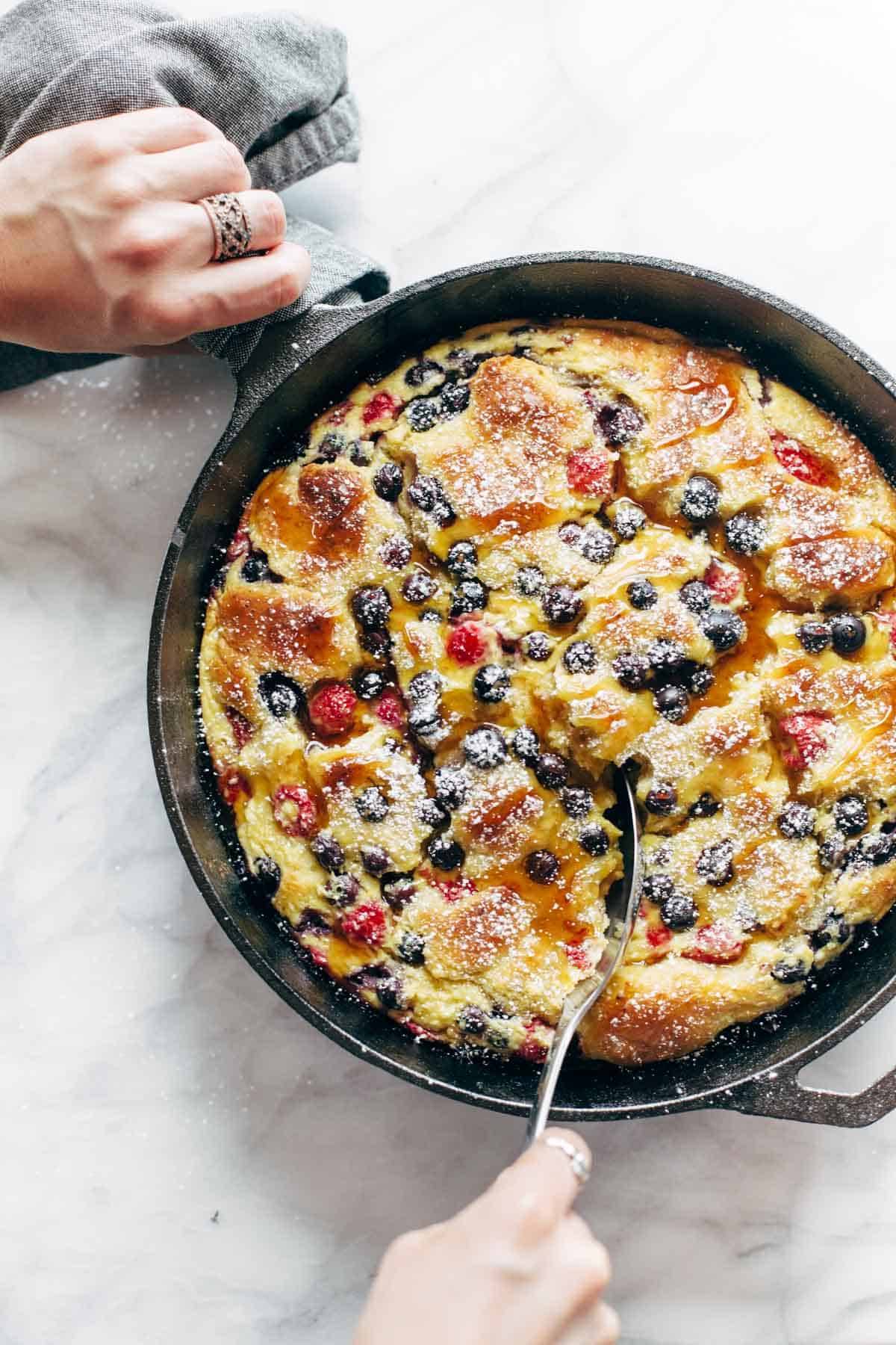 French toast casserole in a pan with two hands.