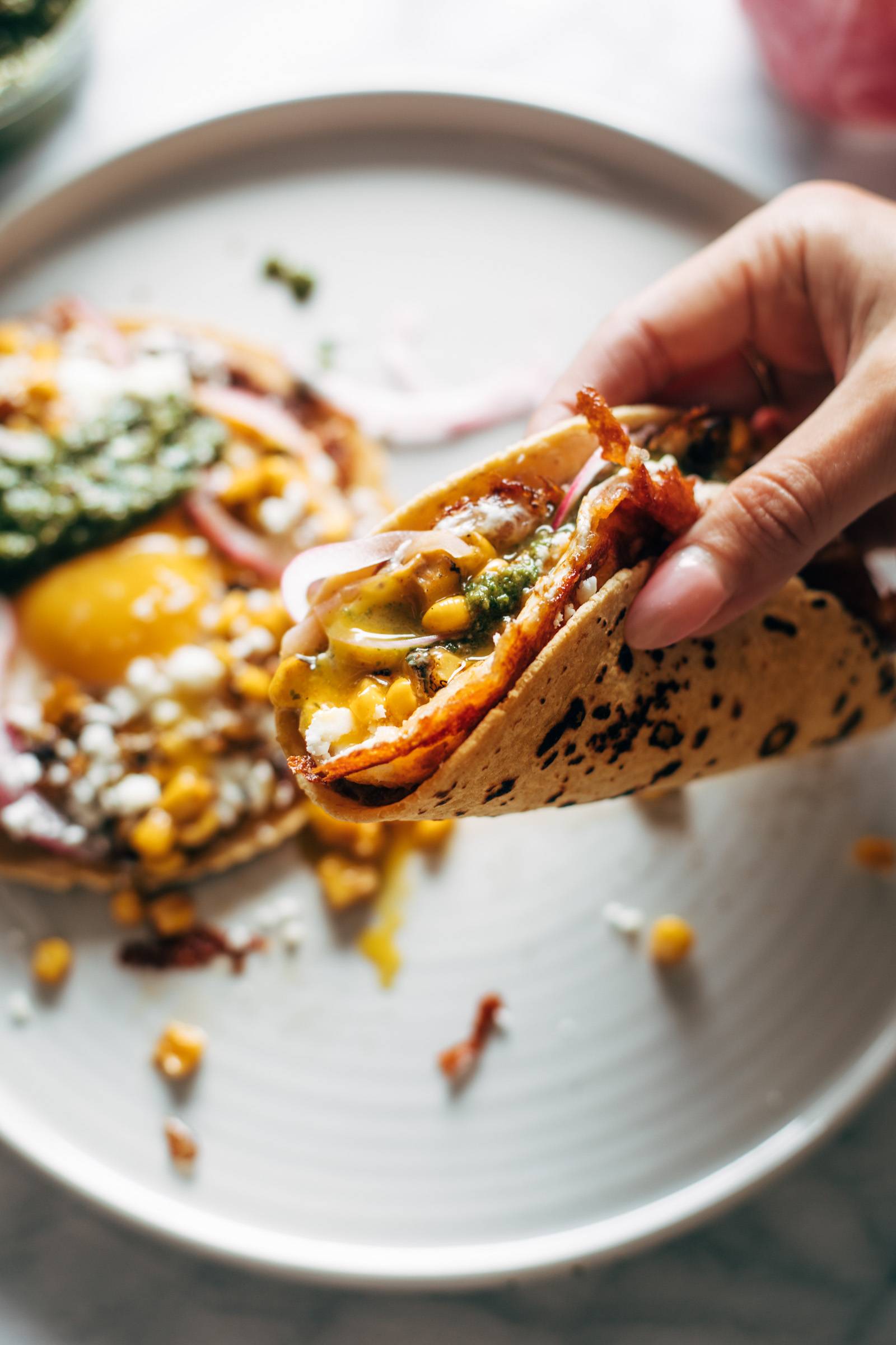 Hand picking up a fried egg taco.