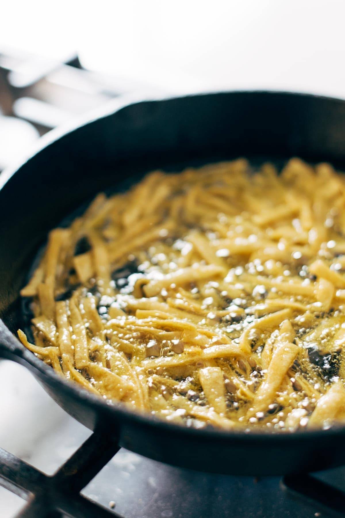 Tortilla strips frying in oil.