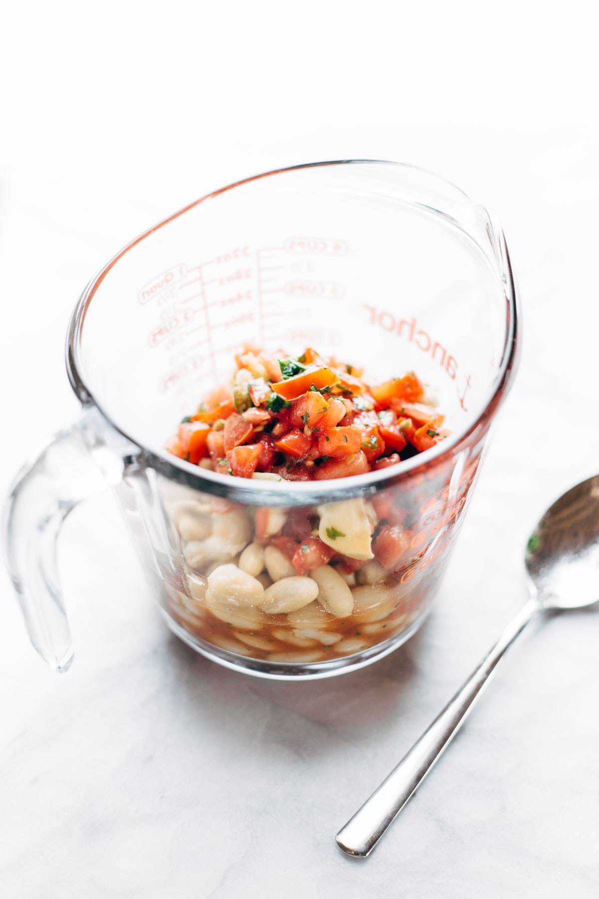 Tomatoes for Barramundi Skillet in a measuring cup with a spoon.