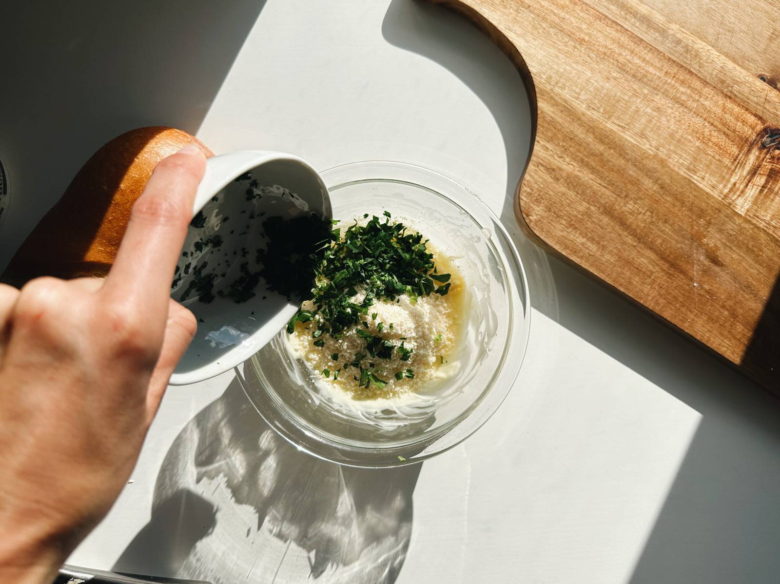 Adding parmesan and parsley to the bowl of butter and garlic.