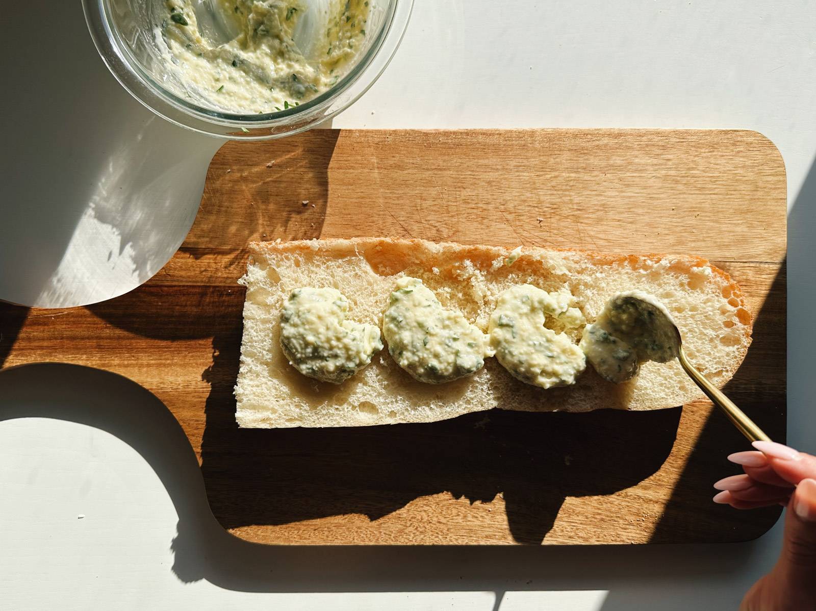 Spreading butter mixture onto half a loaf of bread.