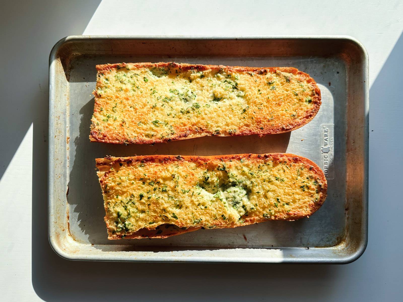 Baked garlic bread on a sheet pan.