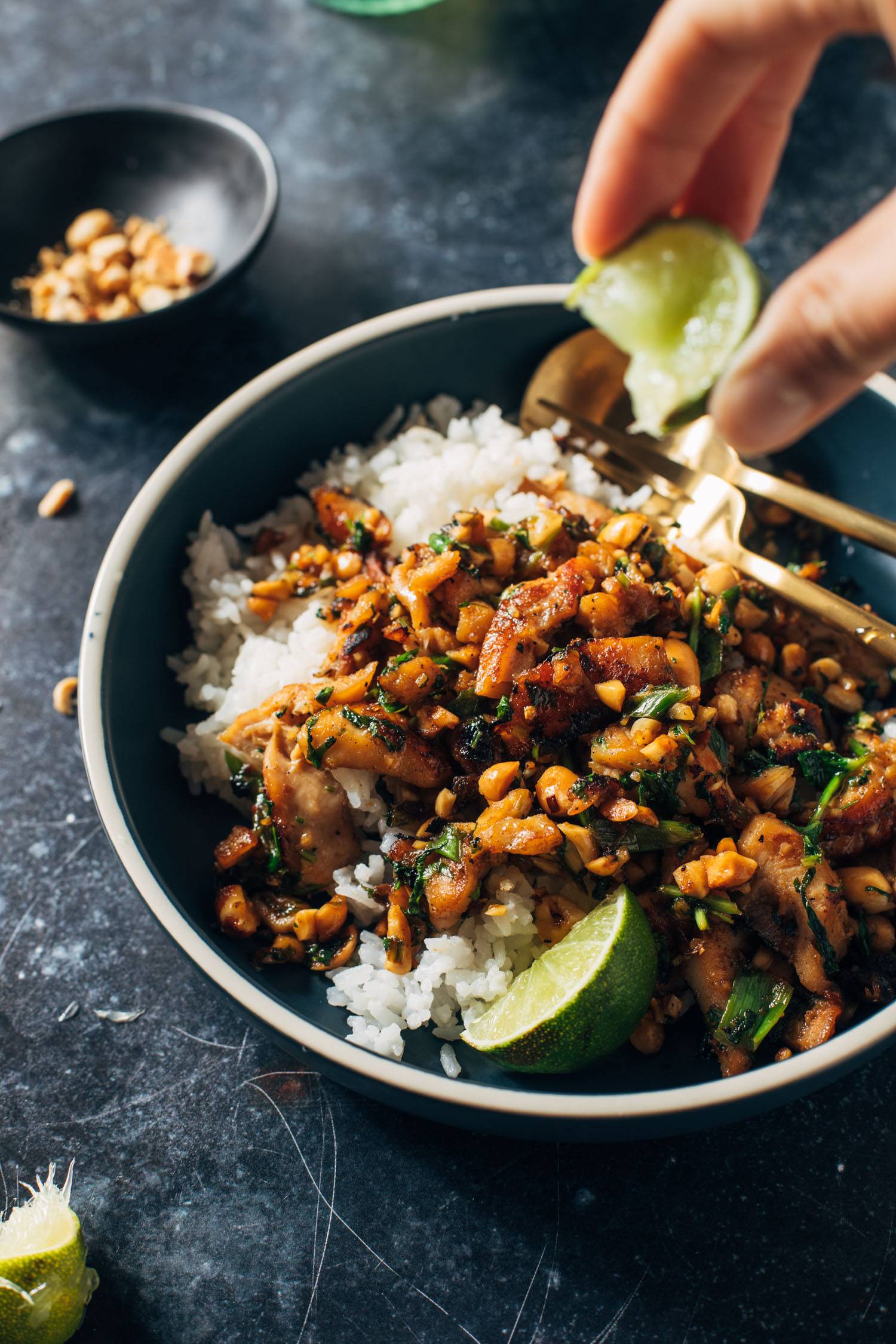 Person squeezing a lime over a bowl of Ginger Peanut Chicken and Coconut Rice.