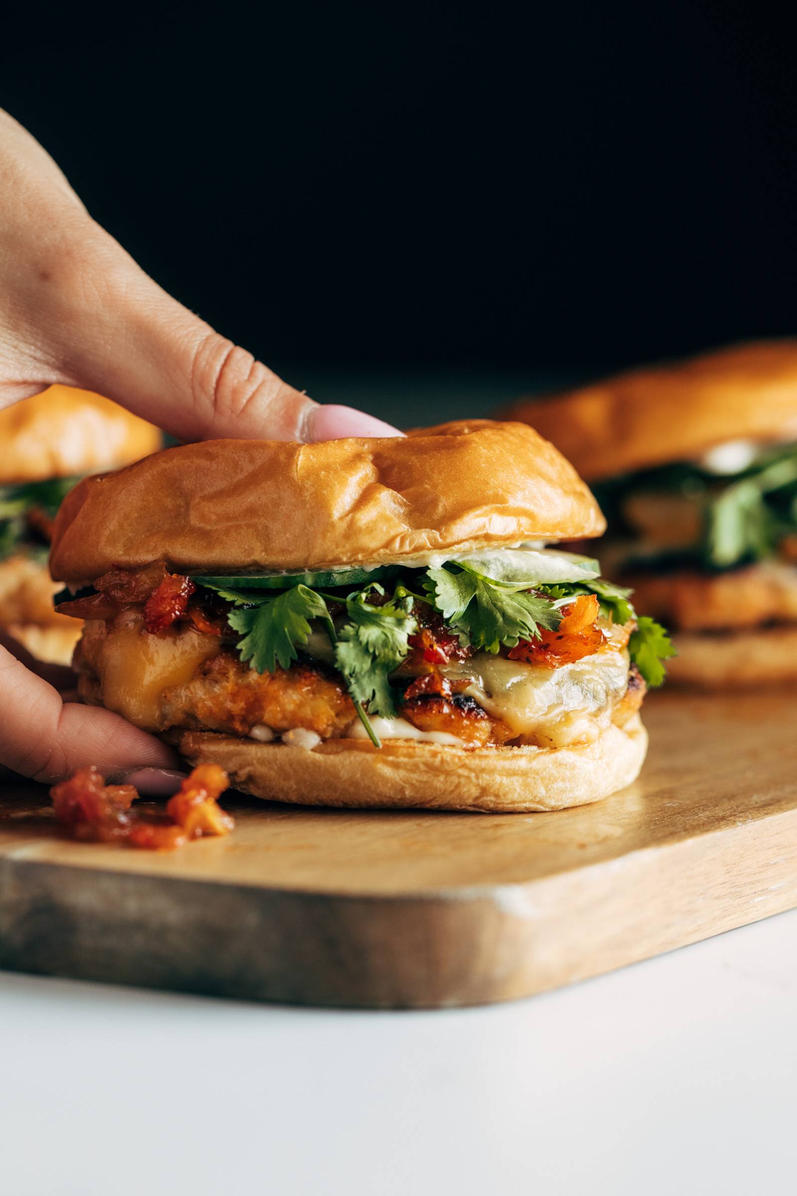 White hand grabbing a gochujang chicken burgers