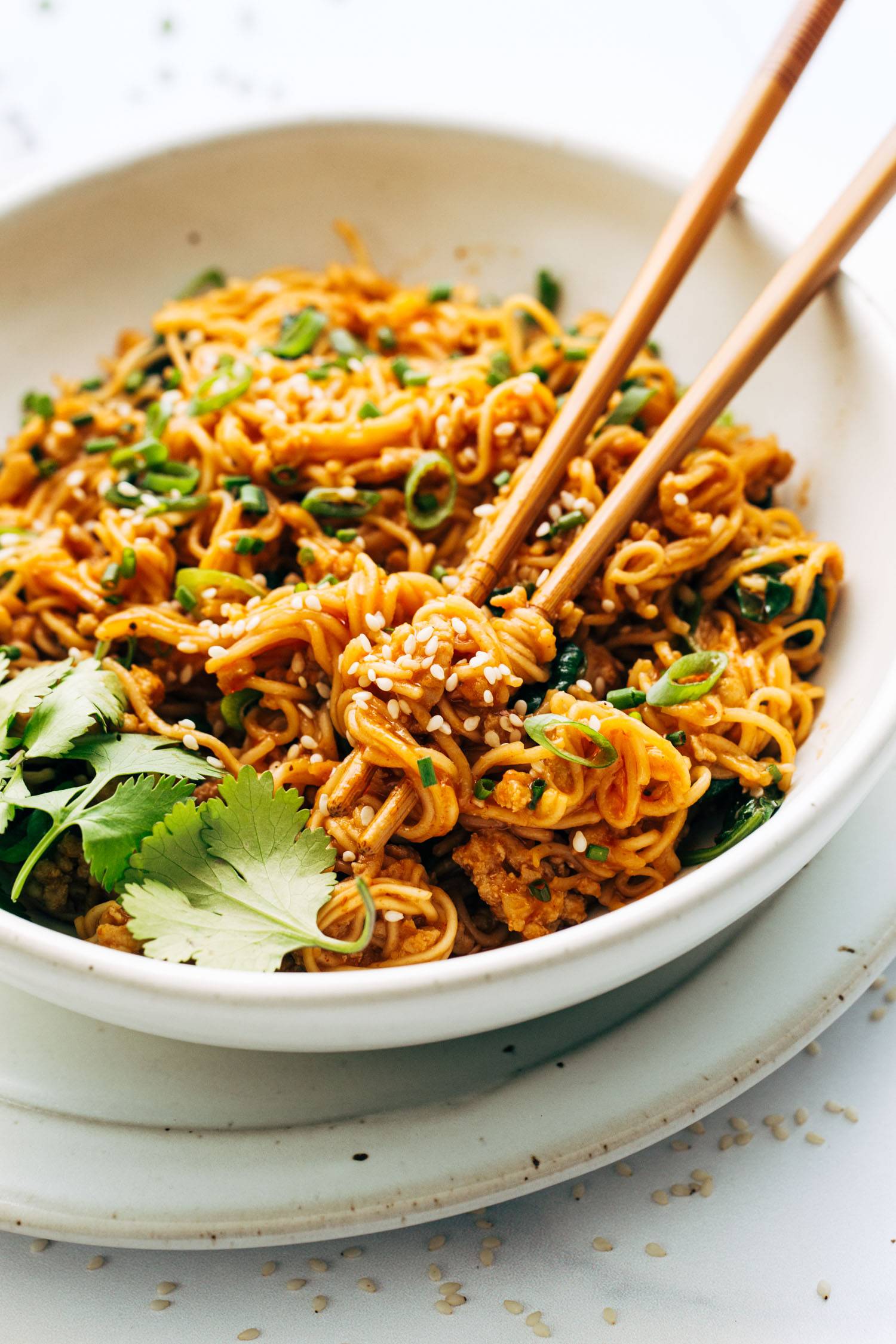 Chopsticks grabbing noodles in a bowl.