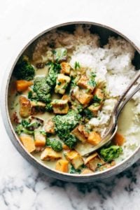 Utensils sit in a bowl of rice, vegetables and tofu.