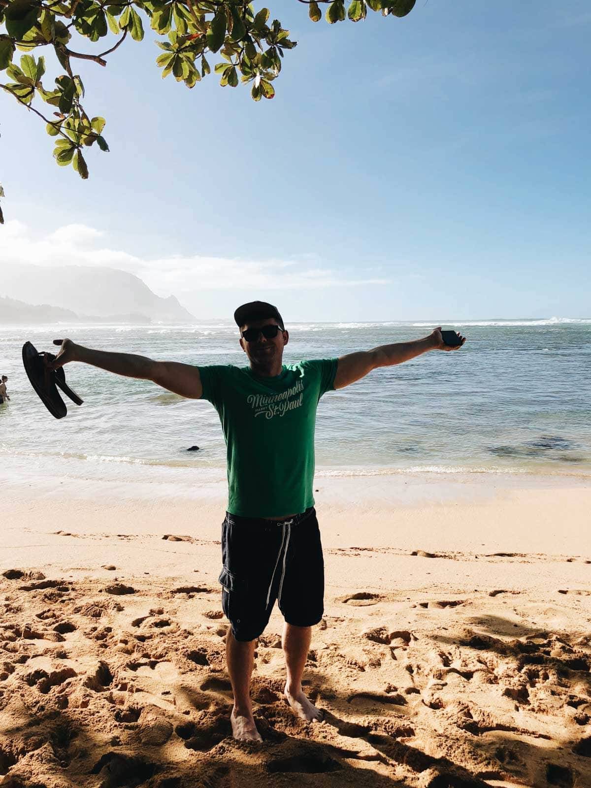 Man with his arms spread on the beach.