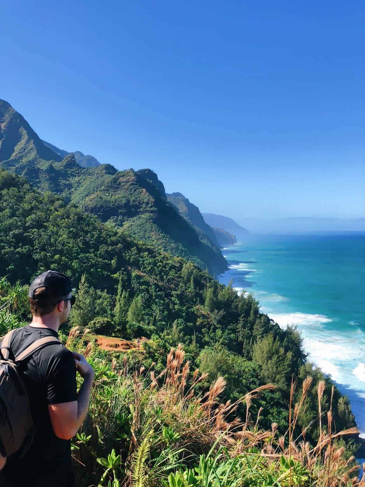 Man standing on a cliff looking out at the ocean.