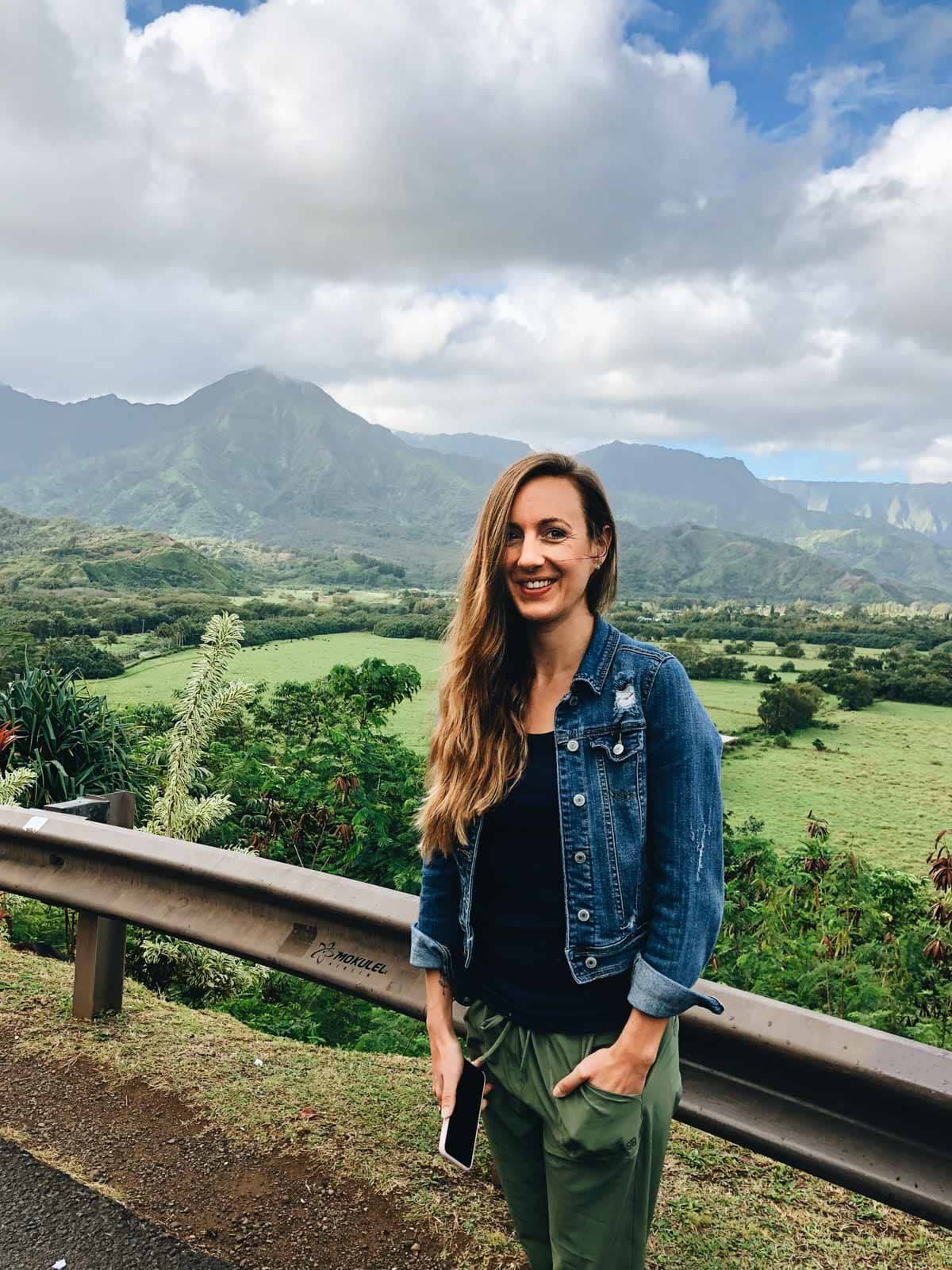 Woman standing on a road in front of mountains.