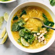 Chicken and rice soup with leafy herbs and a lime wedge.