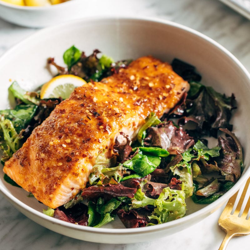 A piece of salmon sitting on a bed of greens.