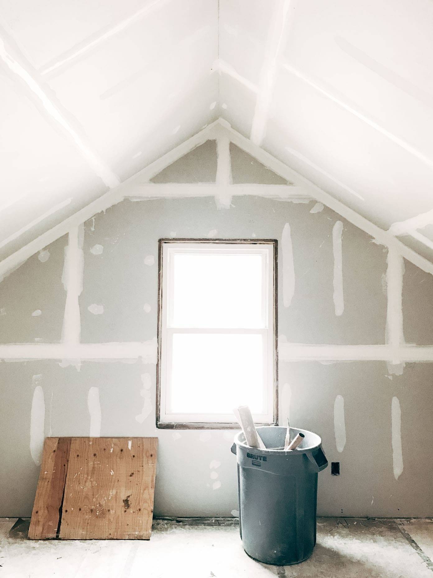 A bucket of paint in an attic being remodelled.