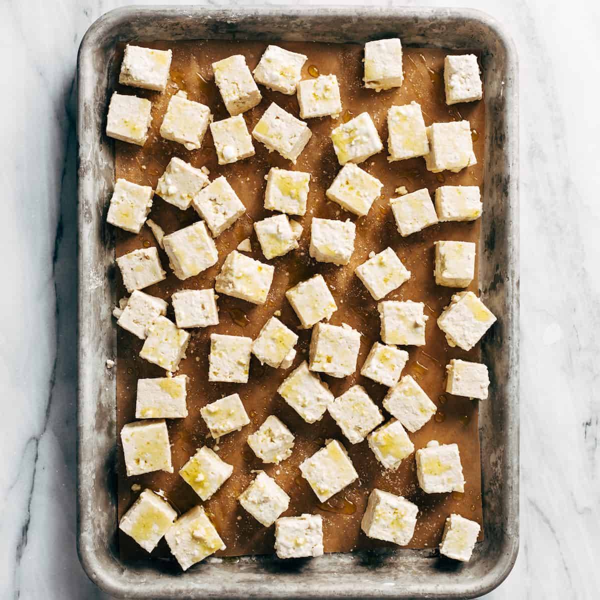 Tofu spread on a baking sheet before baking.