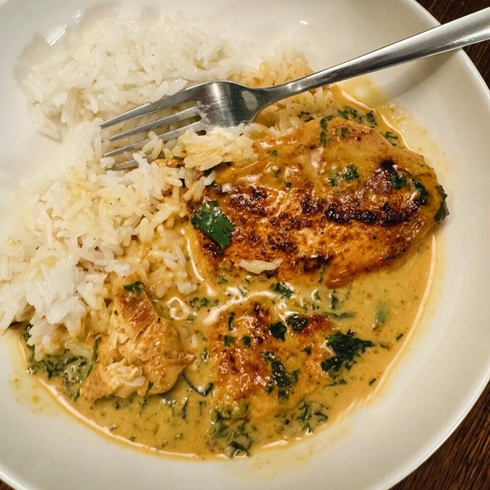 Bowl of chicken with coconut kale and white rice.