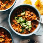 Queso chicken chili in a bowl with avocado on top.