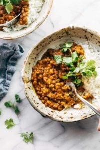 Red curry lentils with rice in a bowl with spoon.