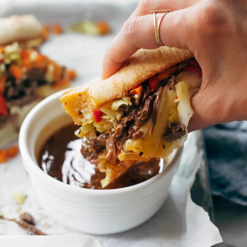 Instant Pot Italian Beef sandwich being dipped in a sauce.