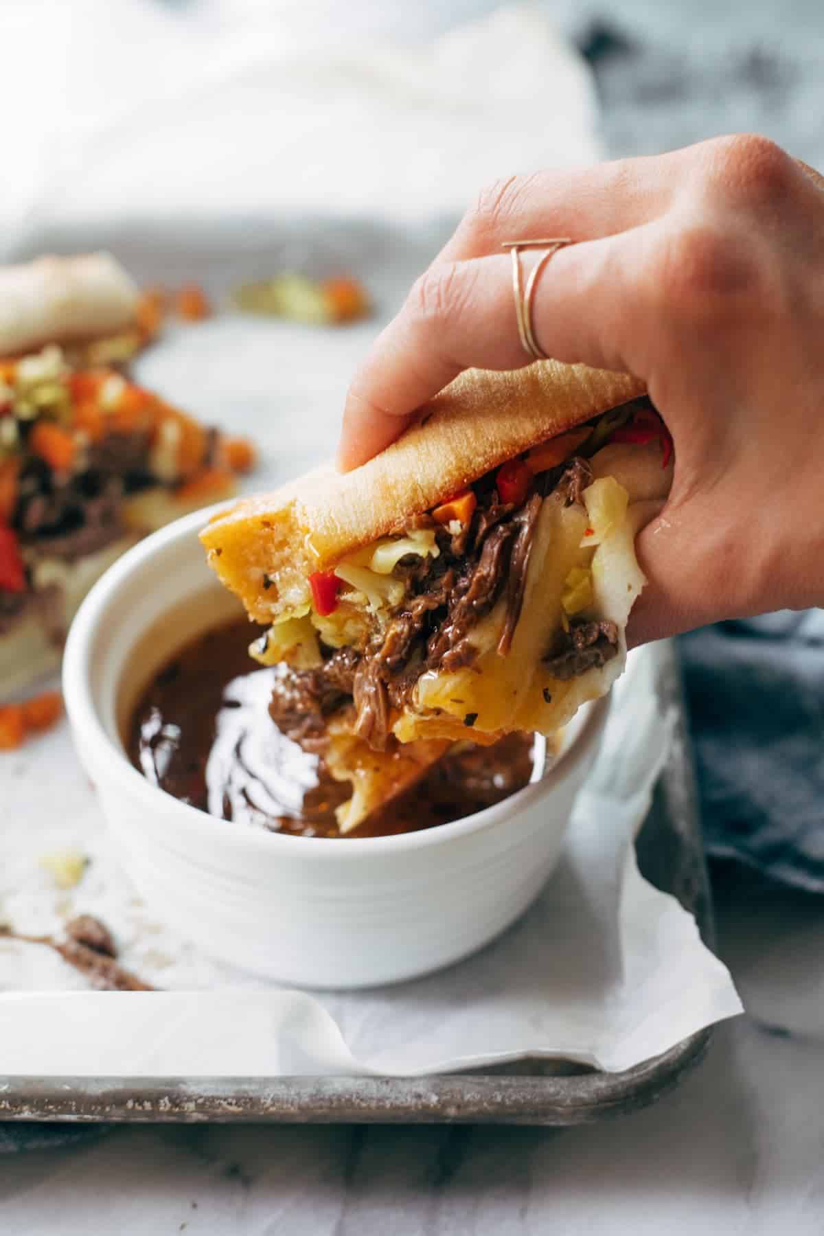 Dipping Italian beef sandwich into sauce.