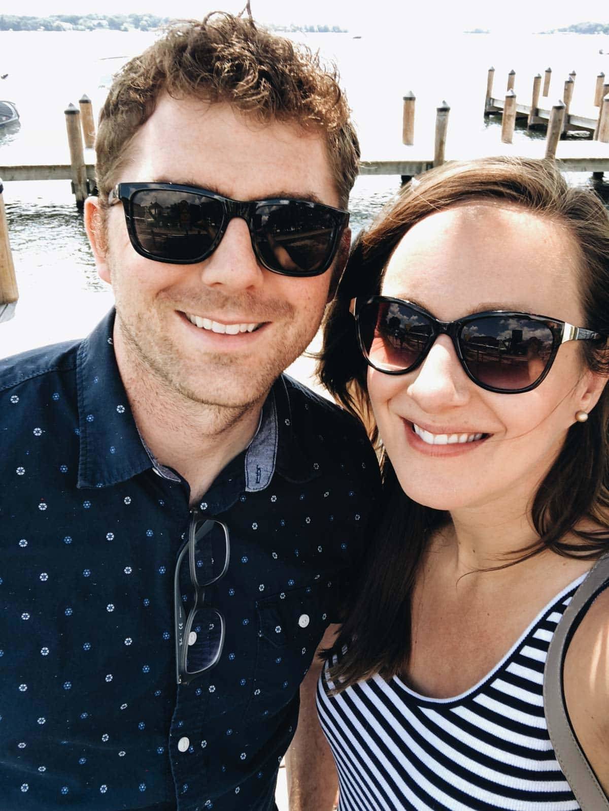 A man and a woman smile in front of a dock.