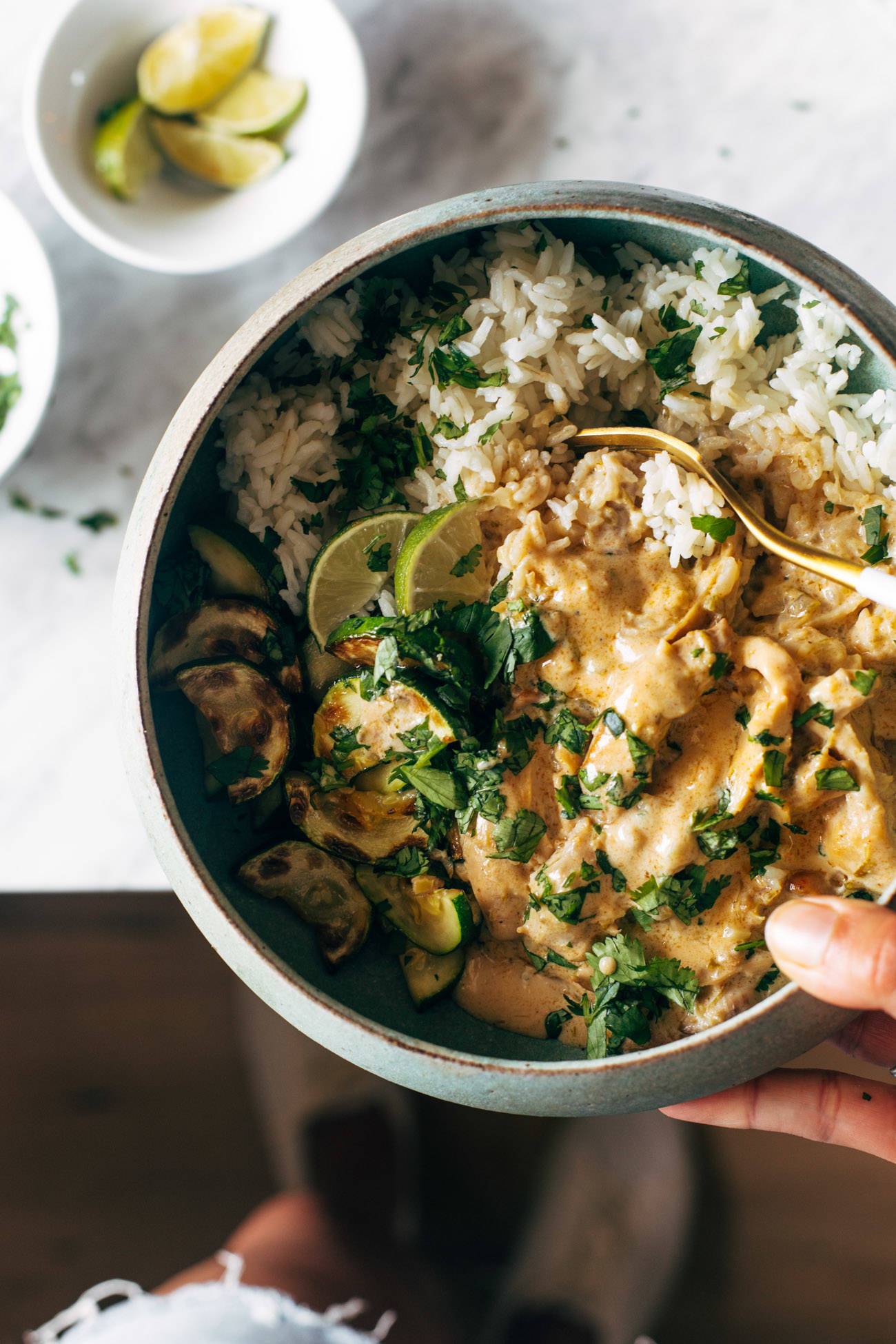 Lemongrass chicken in a bowl with a fork  being held by a white hand. 