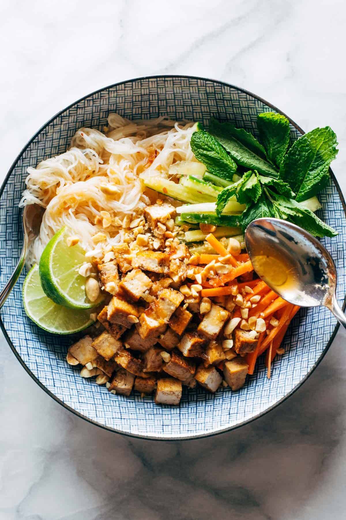 Vermicelli salad in a bowl with sauce spooned over top.