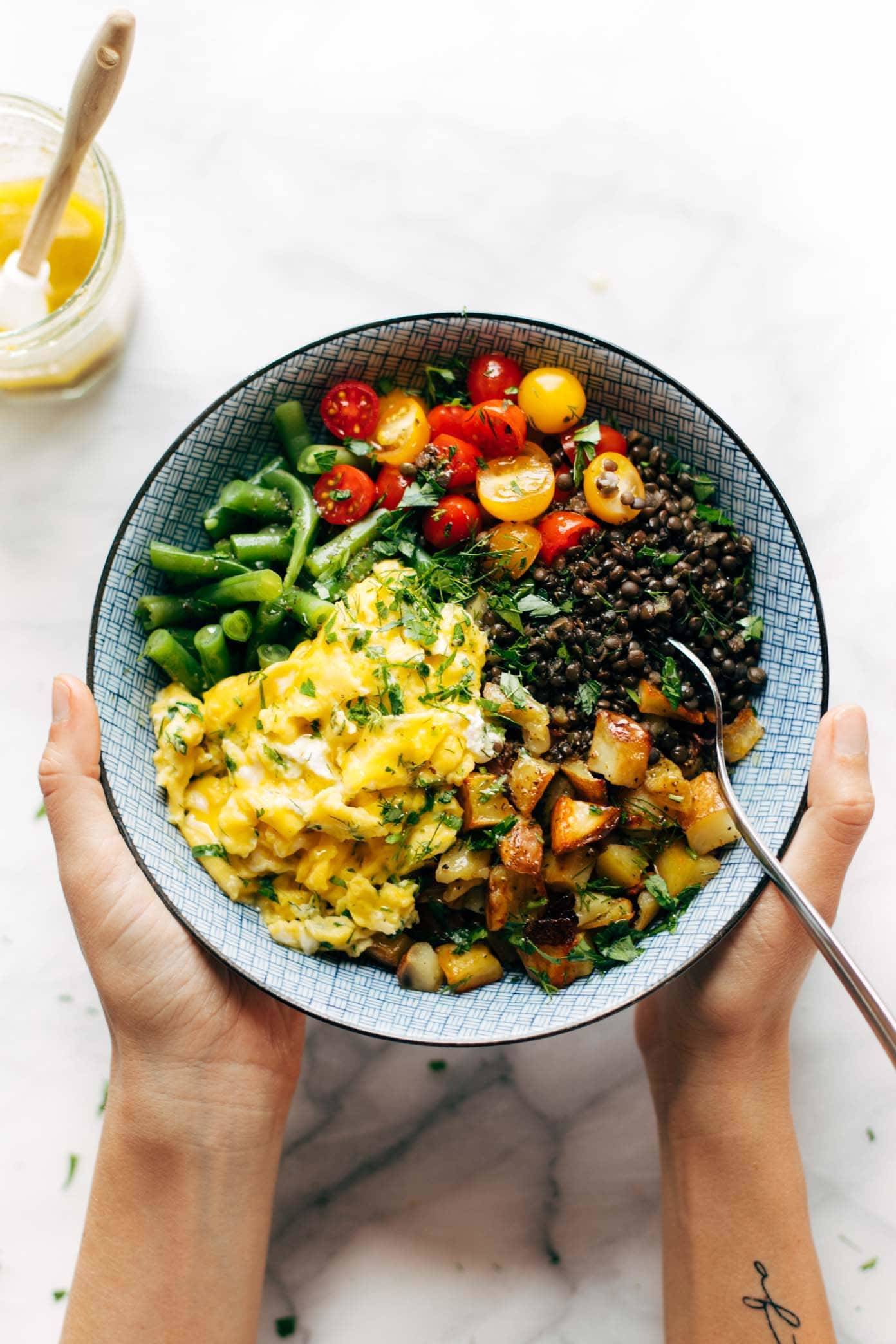 Hands Holding Sunshine Lentil Bowl.