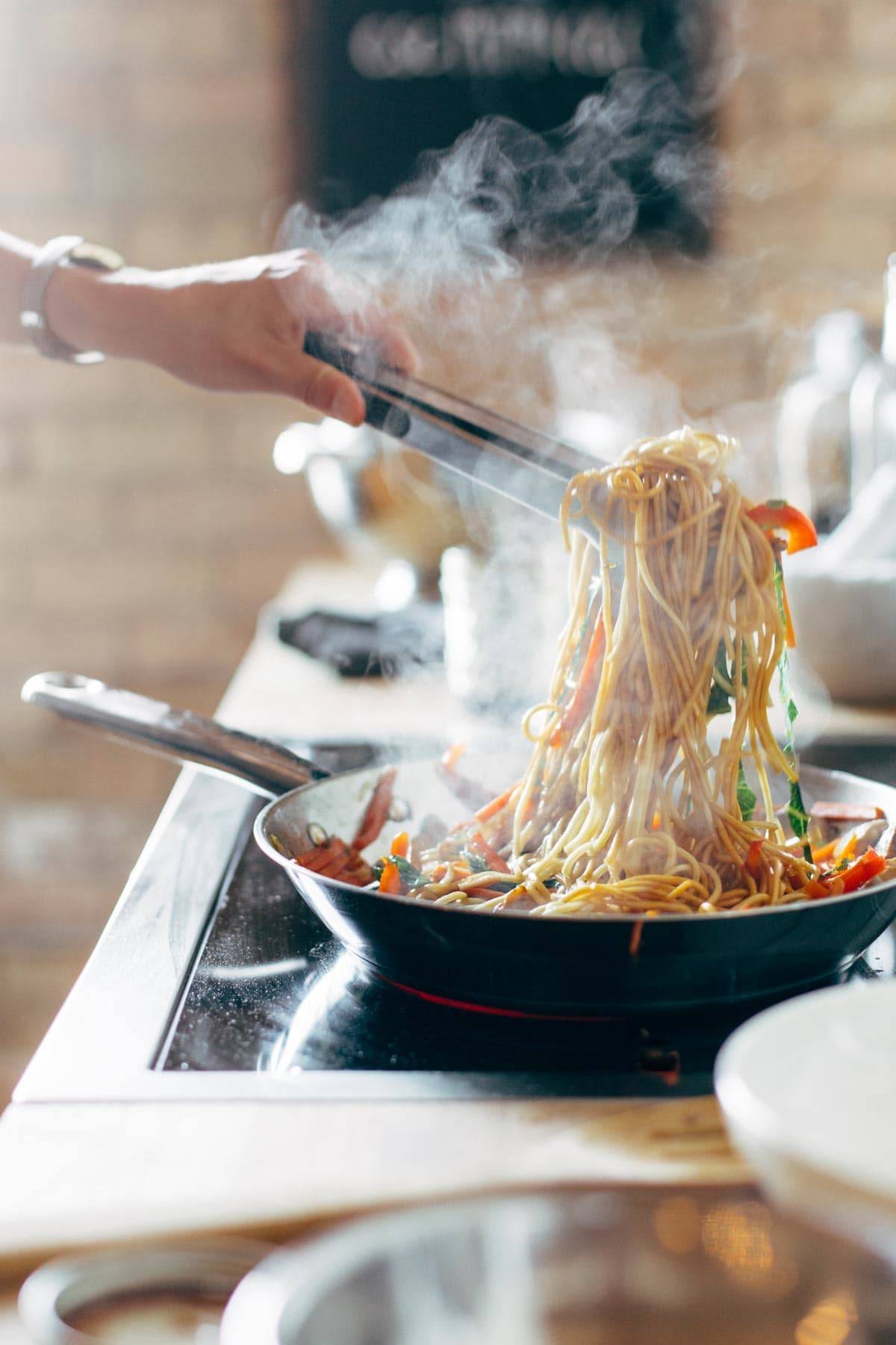 Tossing Lo Mein together in a pan.