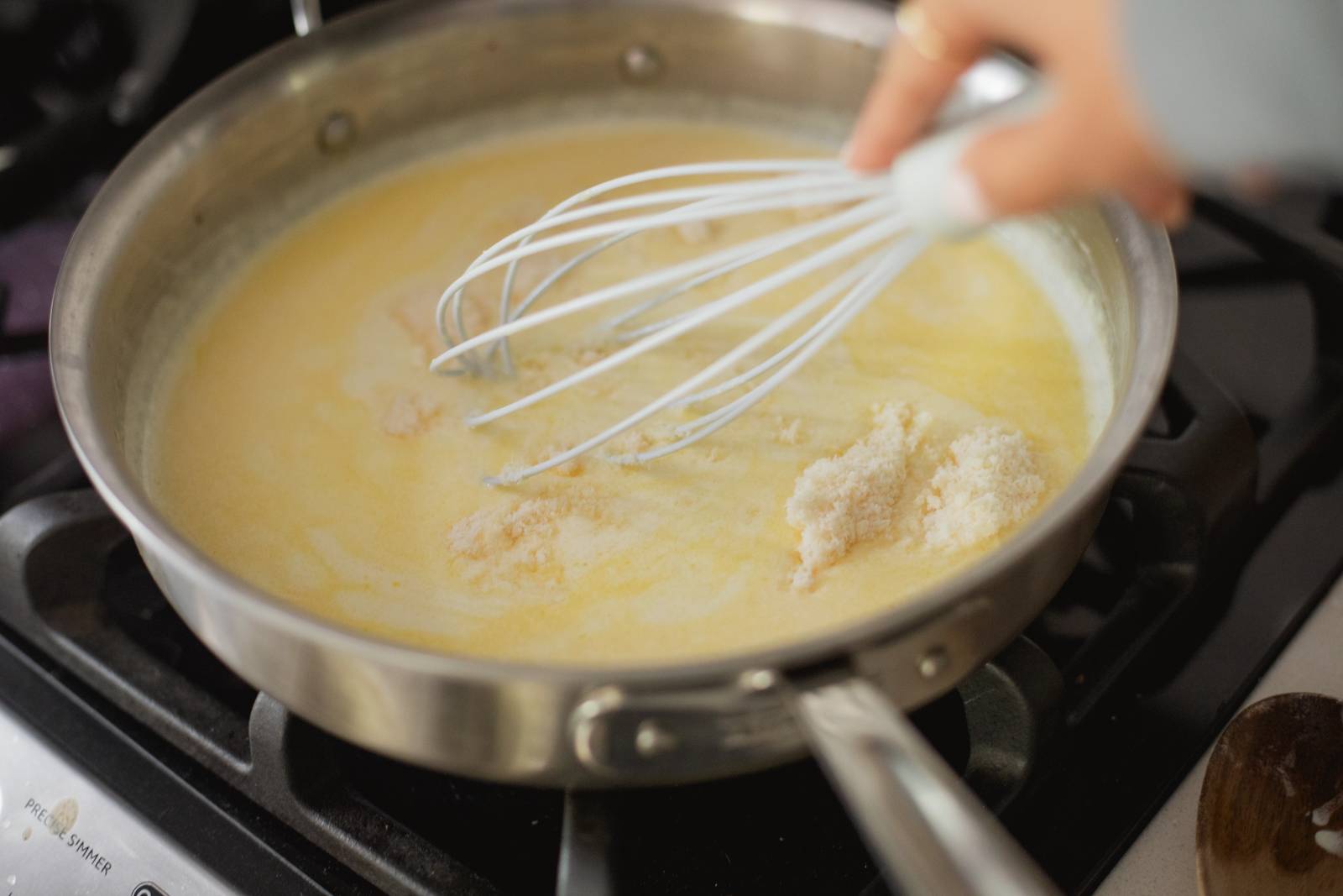 Whisking Parmesan cheese into the sauce.